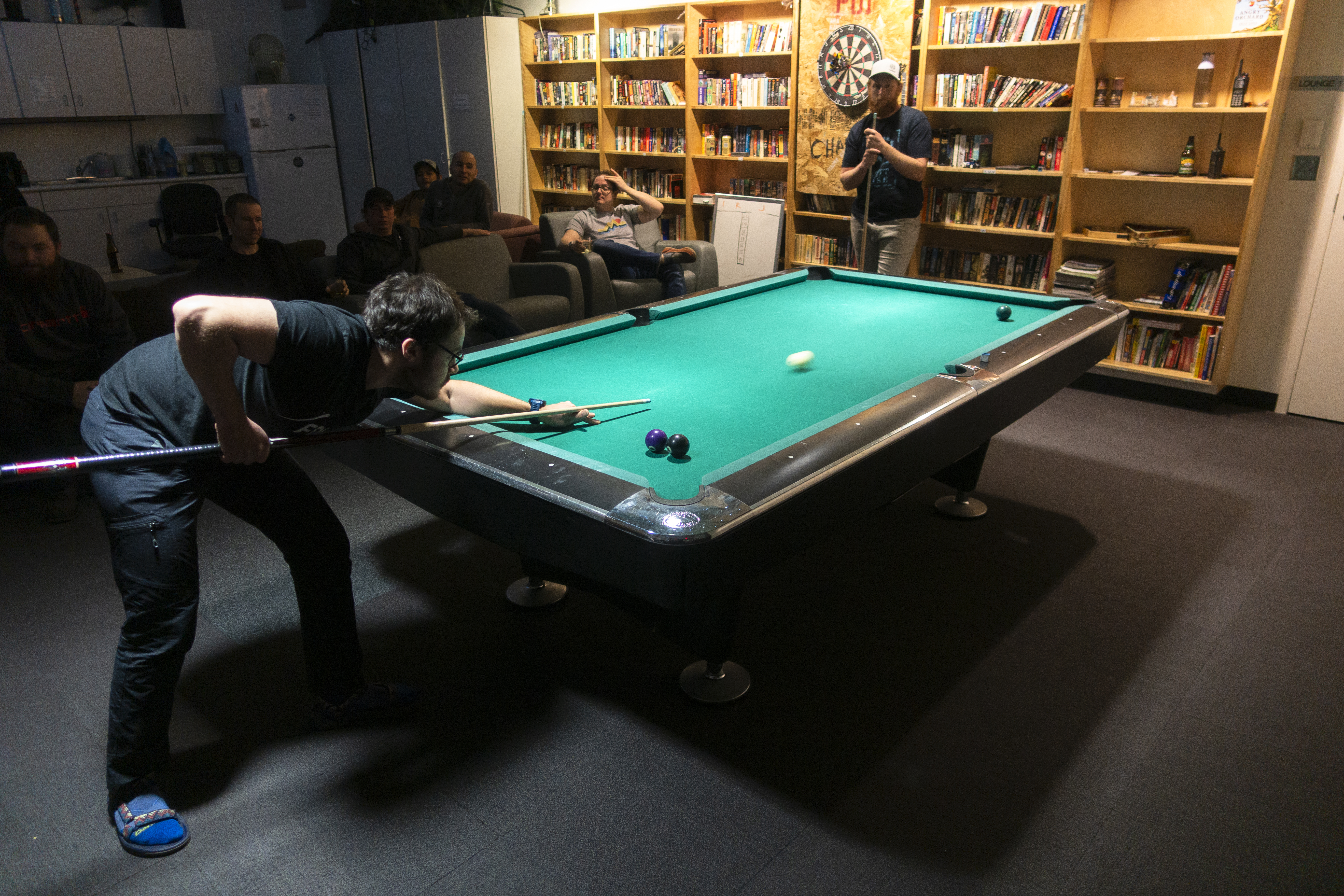 Person bent over pool table in middle of a shot.