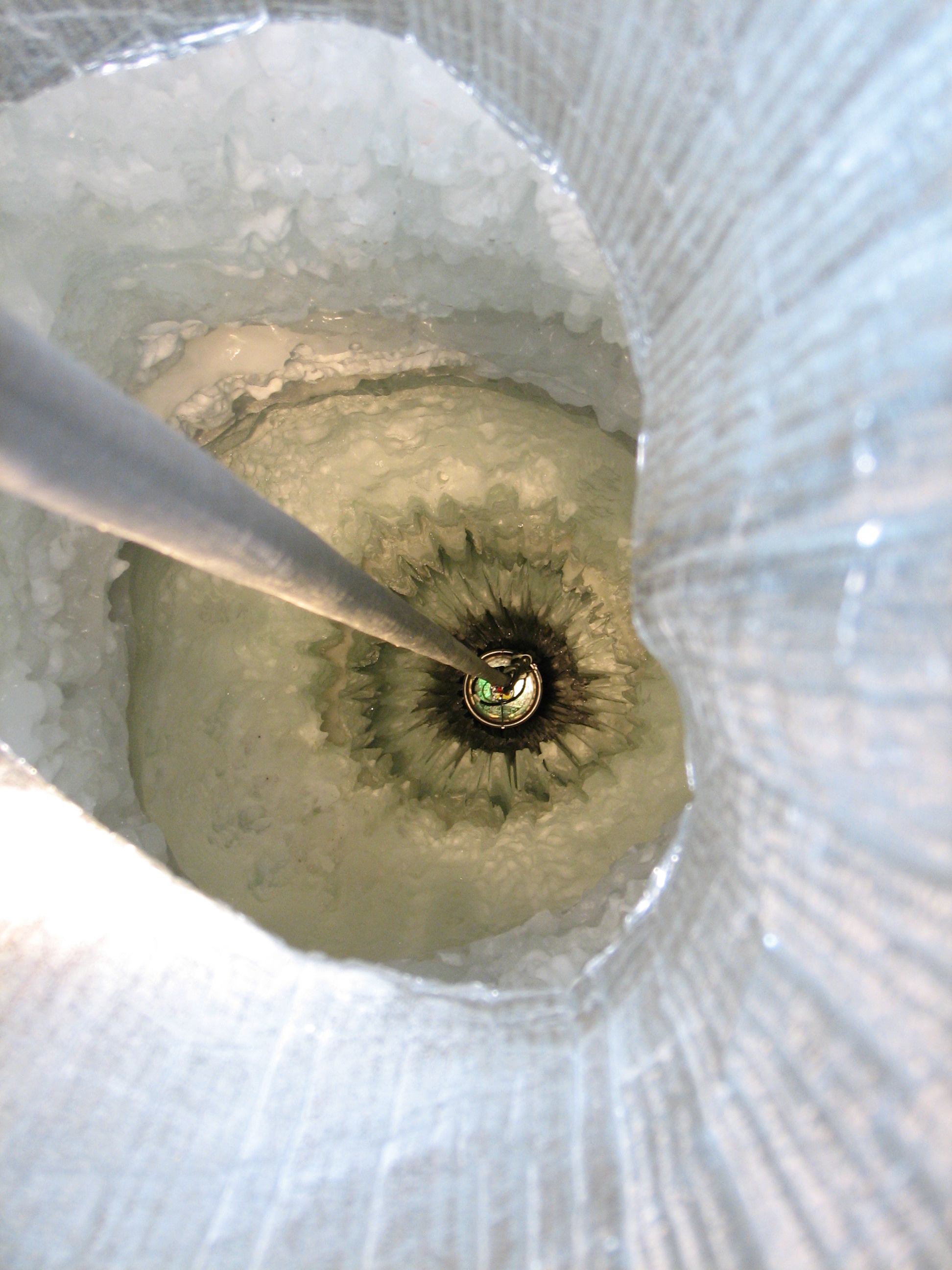 A DOM lowered into the hole of an IceCube string